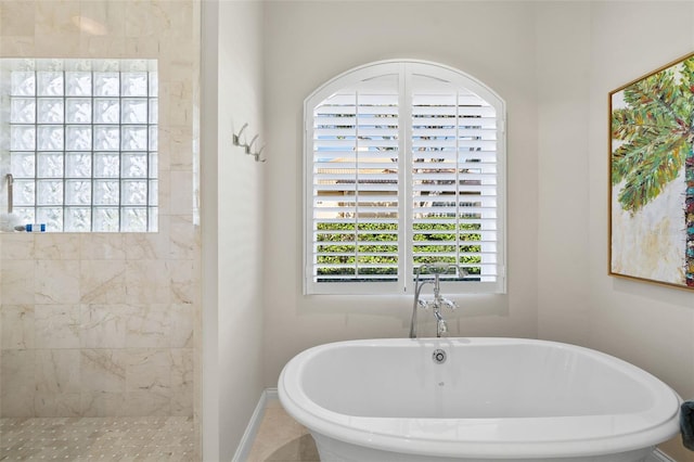 full bath featuring a freestanding tub, baseboards, and a tile shower