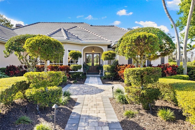 exterior space featuring stucco siding, a tile roof, and french doors