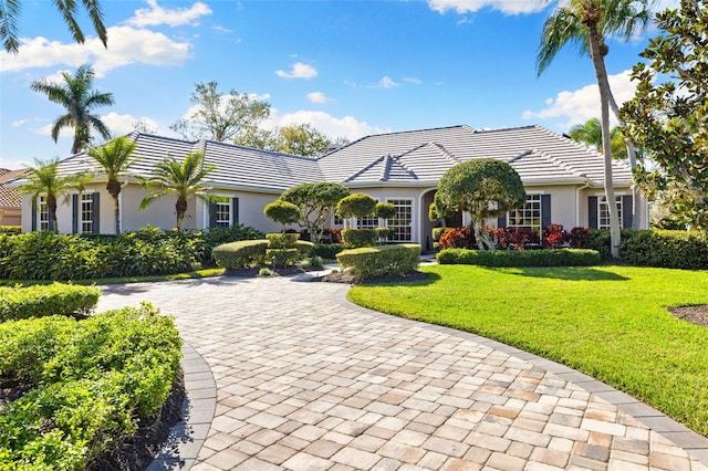 view of front of property with a tiled roof, a front lawn, and stucco siding