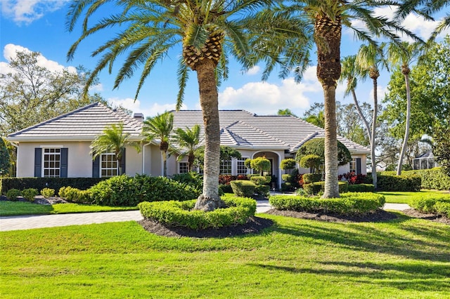 view of front of property with stucco siding, a tiled roof, and a front yard