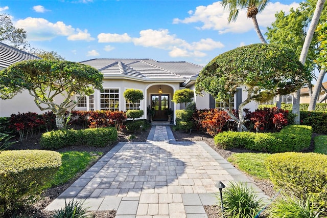 view of front facade with french doors, a tile roof, and stucco siding