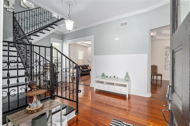 entryway with visible vents, baseboards, stairs, ornamental molding, and wood-type flooring