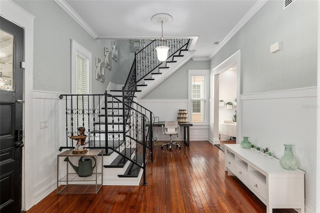 foyer with ornamental molding, hardwood / wood-style floors, stairway, and visible vents