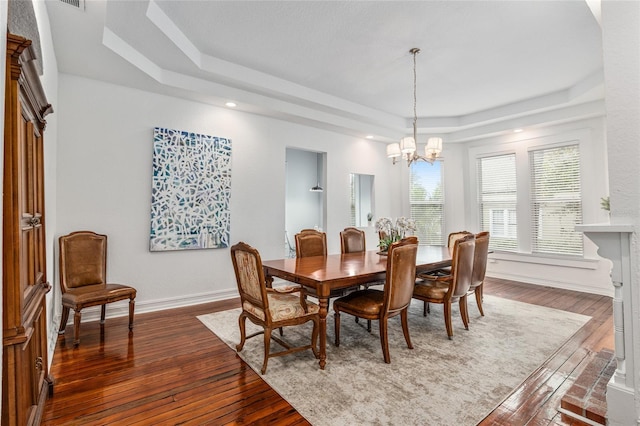 dining room featuring an inviting chandelier, a raised ceiling, dark wood finished floors, and baseboards