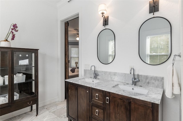 full bath featuring double vanity, marble finish floor, baseboards, and a sink