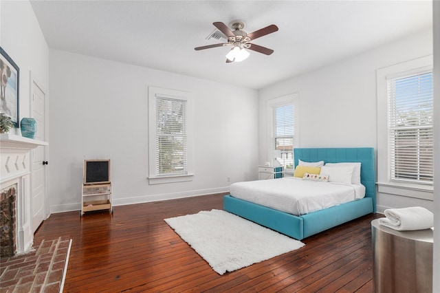 bedroom with baseboards, a fireplace, hardwood / wood-style floors, and ceiling fan