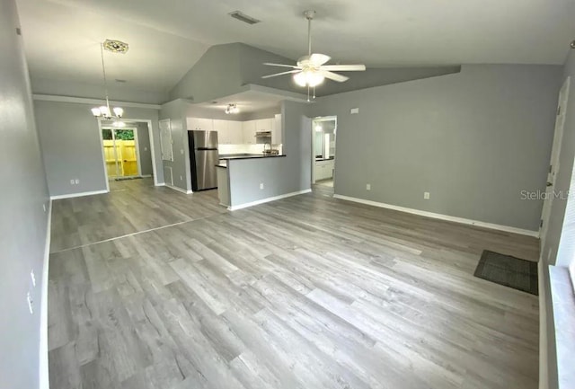 unfurnished living room with wood finished floors, visible vents, baseboards, lofted ceiling, and ceiling fan with notable chandelier