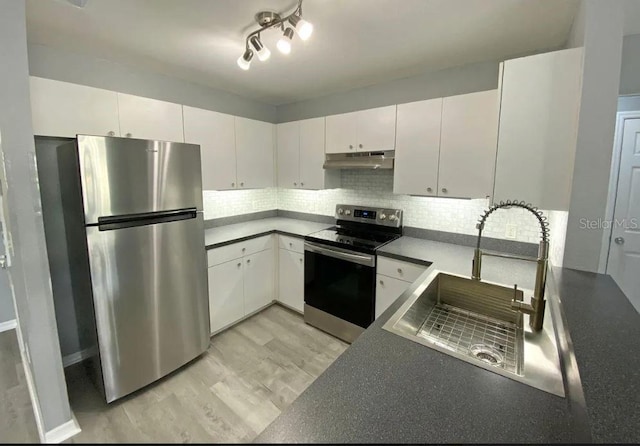 kitchen with a sink, stainless steel appliances, under cabinet range hood, white cabinetry, and backsplash