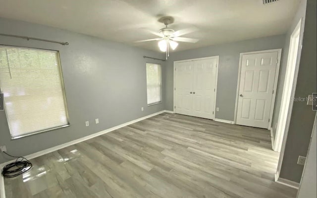 unfurnished bedroom featuring ceiling fan, a closet, baseboards, and wood finished floors