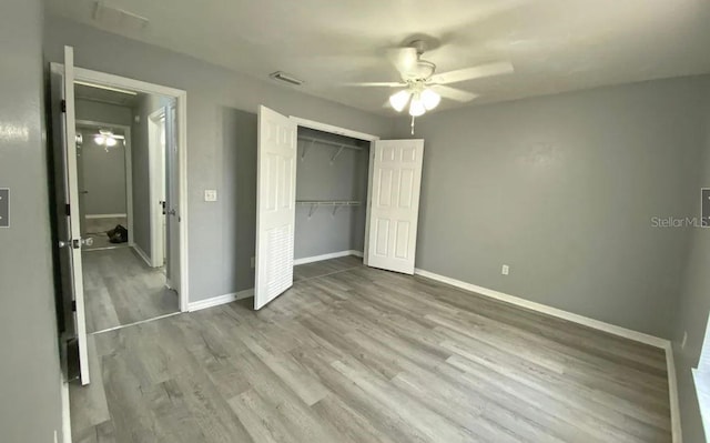 unfurnished bedroom featuring wood finished floors, visible vents, baseboards, ceiling fan, and a closet