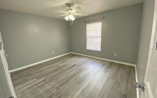 empty room featuring ceiling fan, baseboards, and wood finished floors