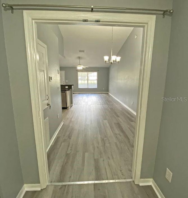 interior space with baseboards, an inviting chandelier, and wood finished floors