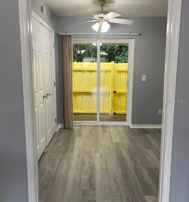 spare room featuring wood finished floors, baseboards, and ceiling fan