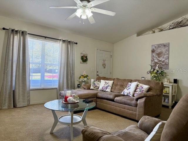 living area featuring lofted ceiling, a ceiling fan, and carpet flooring