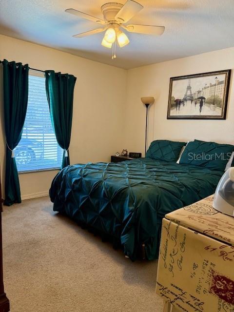 carpeted bedroom featuring baseboards and a ceiling fan