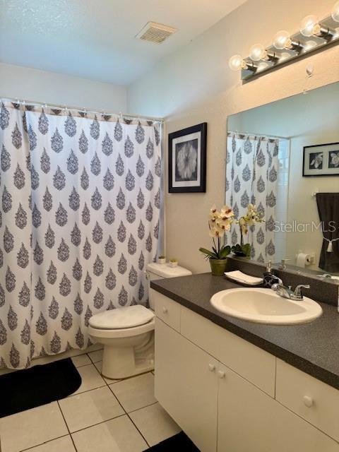 full bath with vanity, a shower with shower curtain, visible vents, tile patterned flooring, and toilet