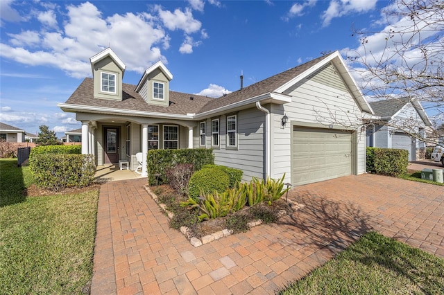 new england style home with a garage, roof with shingles, and decorative driveway