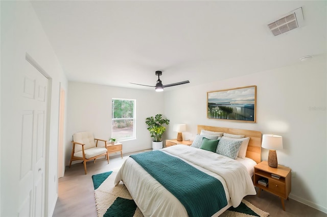 bedroom featuring visible vents, baseboards, ceiling fan, and wood finished floors