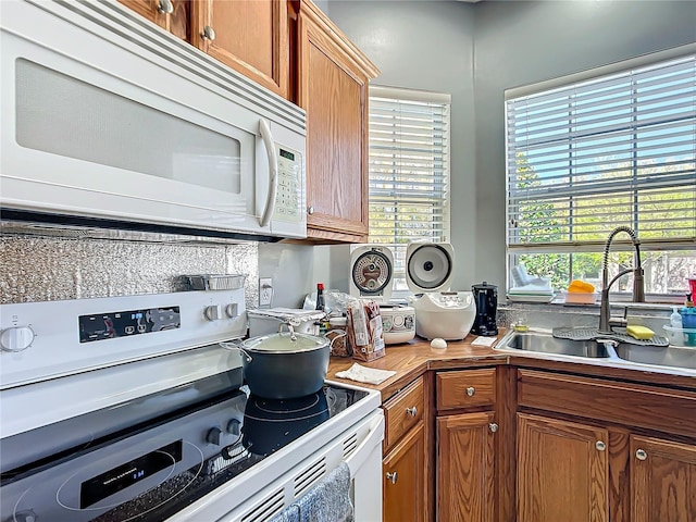 kitchen with white appliances, brown cabinets, and a sink