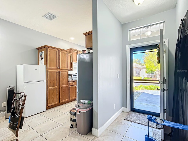 entrance foyer with visible vents, a textured ceiling, baseboards, and light tile patterned floors