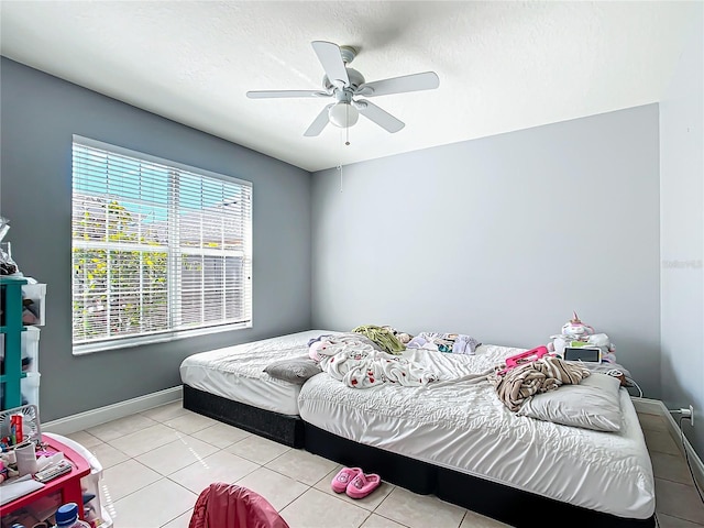 bedroom featuring a textured ceiling, light tile patterned flooring, a ceiling fan, and baseboards