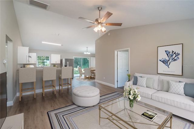 living area featuring lofted ceiling, visible vents, ceiling fan, wood finished floors, and baseboards