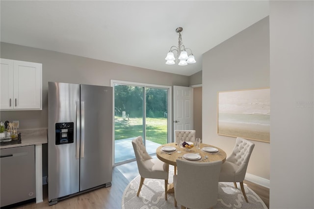 dining room with lofted ceiling, a notable chandelier, light wood-style flooring, and baseboards