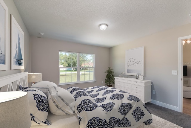 bedroom with a textured ceiling, carpet flooring, and baseboards