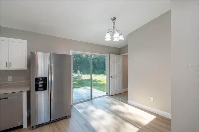 kitchen with light wood finished floors, baseboards, white cabinets, appliances with stainless steel finishes, and light countertops