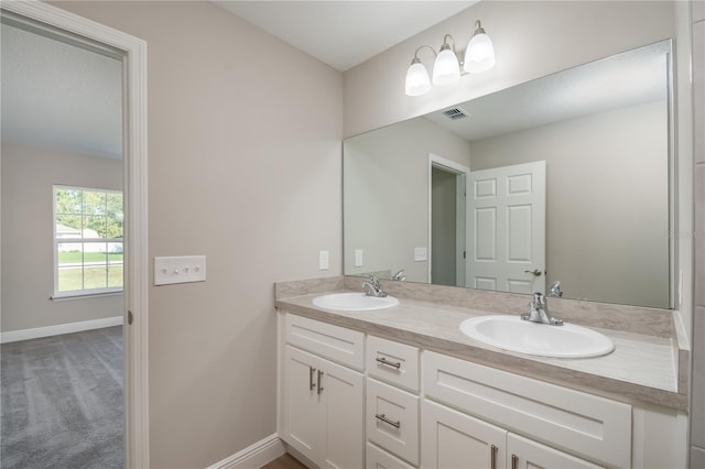 full bath with double vanity, a sink, visible vents, and baseboards