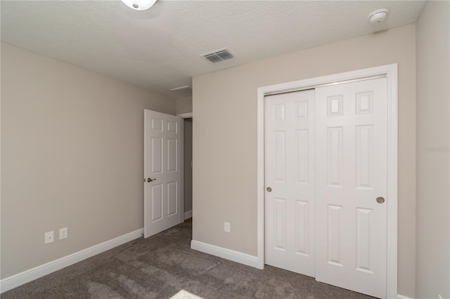 unfurnished bedroom with a textured ceiling, carpet flooring, visible vents, baseboards, and a closet