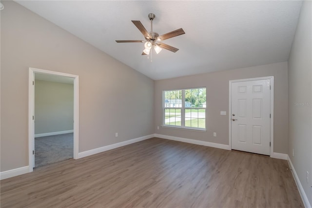 unfurnished room featuring vaulted ceiling, wood finished floors, a ceiling fan, and baseboards