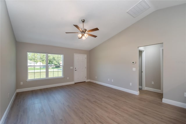 spare room featuring baseboards, visible vents, vaulted ceiling, and wood finished floors