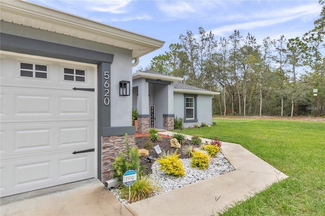 view of exterior entry with a yard, stone siding, stucco siding, and a garage