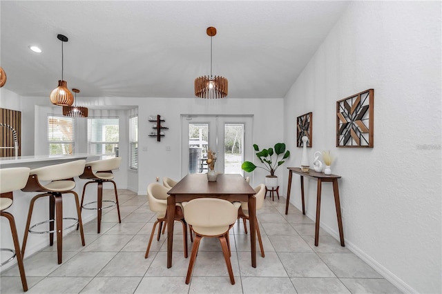 dining space featuring light tile patterned floors, french doors, baseboards, and lofted ceiling