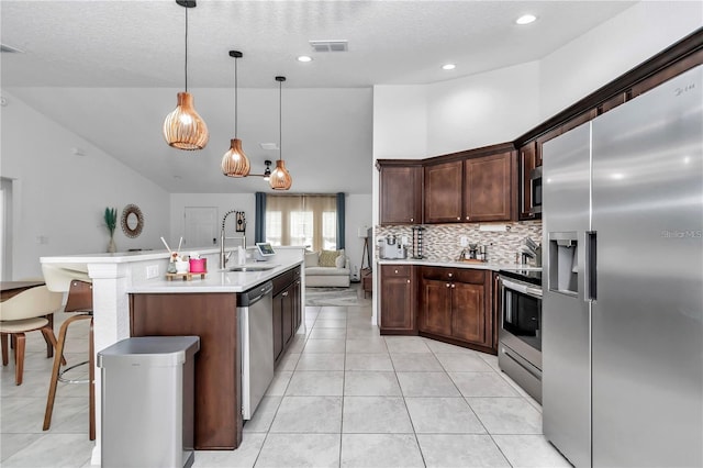 kitchen featuring visible vents, light countertops, decorative backsplash, appliances with stainless steel finishes, and a sink