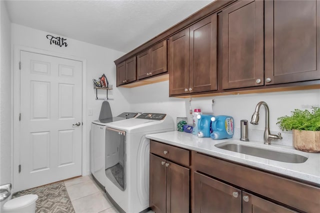 clothes washing area with washing machine and clothes dryer, light tile patterned floors, cabinet space, and a sink