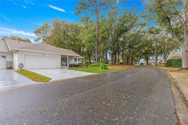 view of front facade featuring a garage, concrete driveway, a front lawn, and a shingled roof