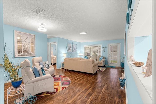 living area featuring a textured ceiling, dark wood-type flooring, and visible vents