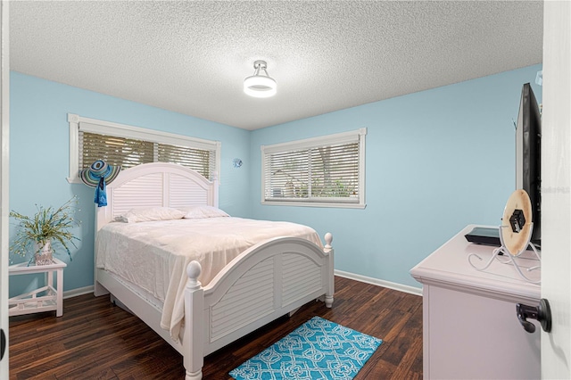 bedroom with dark wood-style floors, a textured ceiling, and baseboards