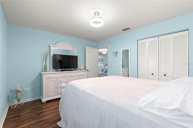 bedroom with baseboards, visible vents, dark wood-style flooring, a textured ceiling, and a closet