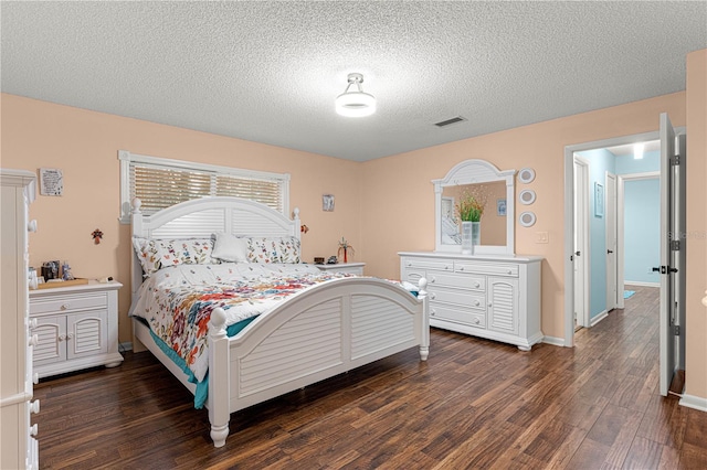 bedroom with a textured ceiling, dark wood-style flooring, visible vents, and baseboards