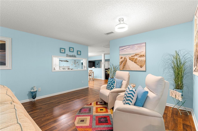 living room featuring a textured ceiling, wood finished floors, visible vents, and baseboards