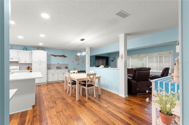 dining room featuring a textured ceiling, wood-type flooring, visible vents, and recessed lighting