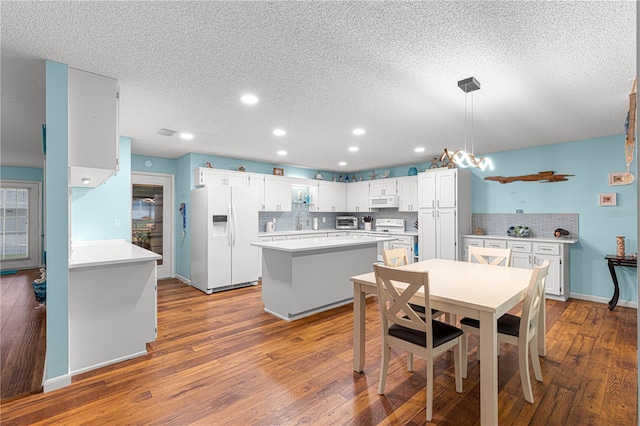 kitchen with white appliances, decorative backsplash, and hardwood / wood-style floors