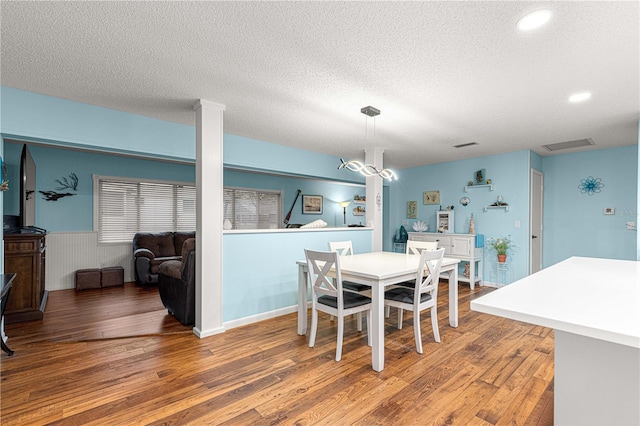 dining space with a textured ceiling, light wood-style flooring, recessed lighting, a wainscoted wall, and visible vents