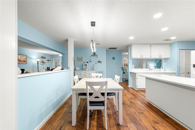 dining room featuring a textured ceiling, recessed lighting, wood finished floors, visible vents, and baseboards