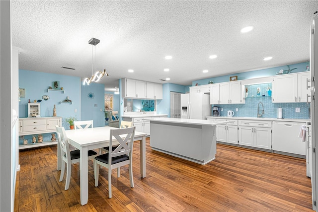 kitchen with dark wood-style floors, light countertops, backsplash, white cabinetry, and white appliances