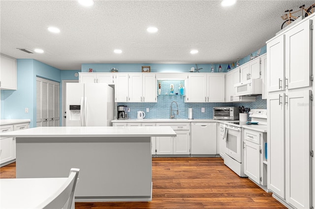 kitchen with a toaster, white appliances, dark wood-style flooring, white cabinetry, and light countertops