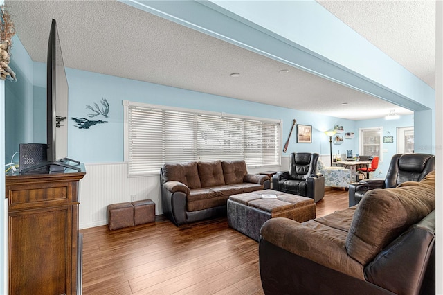 living room featuring a wainscoted wall, a textured ceiling, and wood finished floors